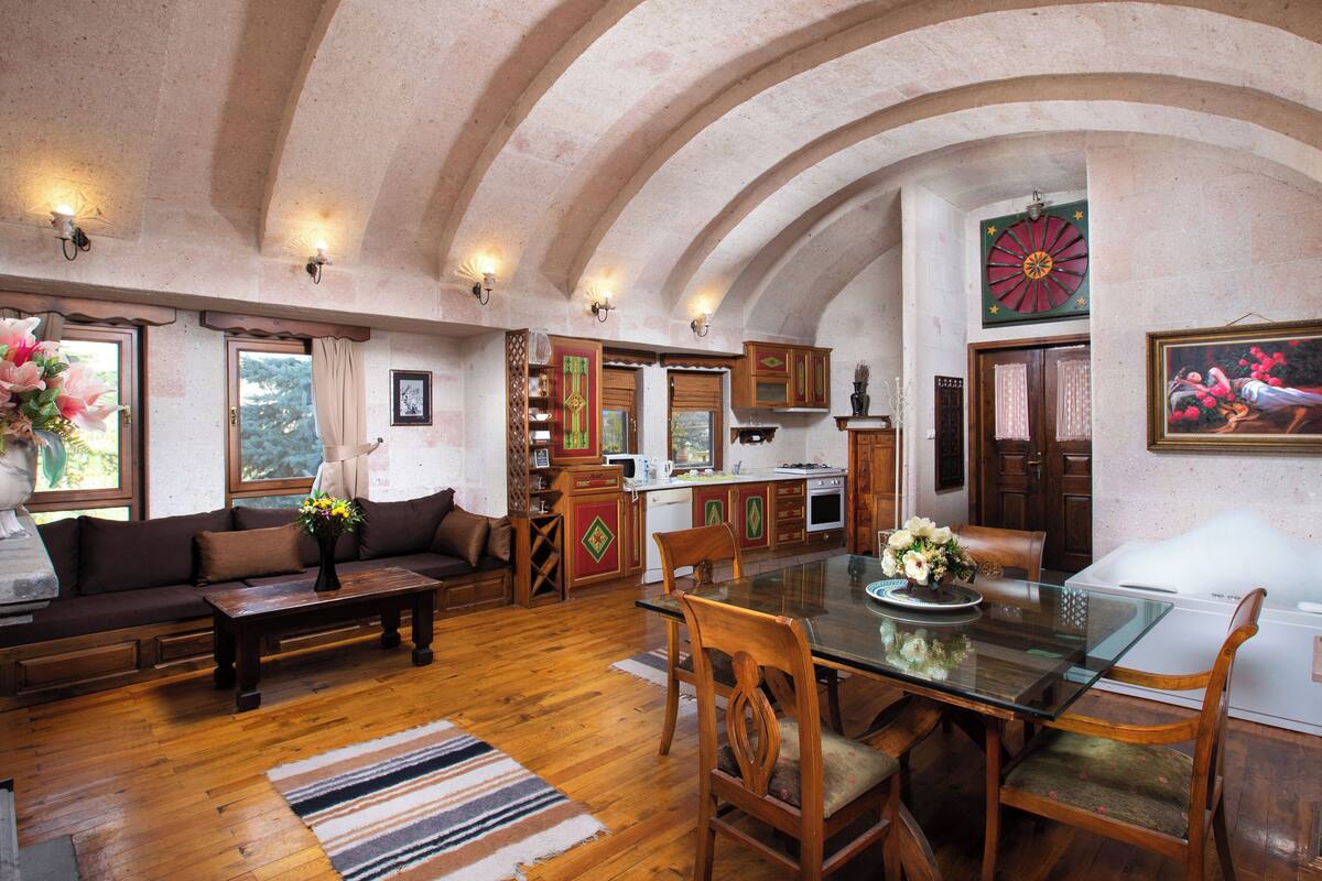 Un espacio habitable amplio con piso de madera, una mesa de comedor de vidrio y una acogedora disposición de asientos.