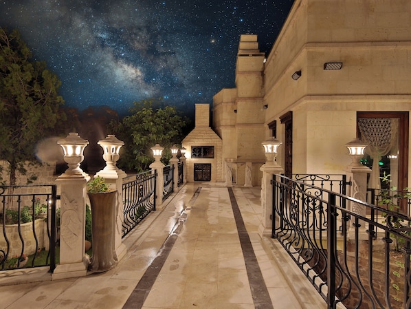 A nighttime view of a building with a starry sky, a stone pathway, and decorative lanterns.