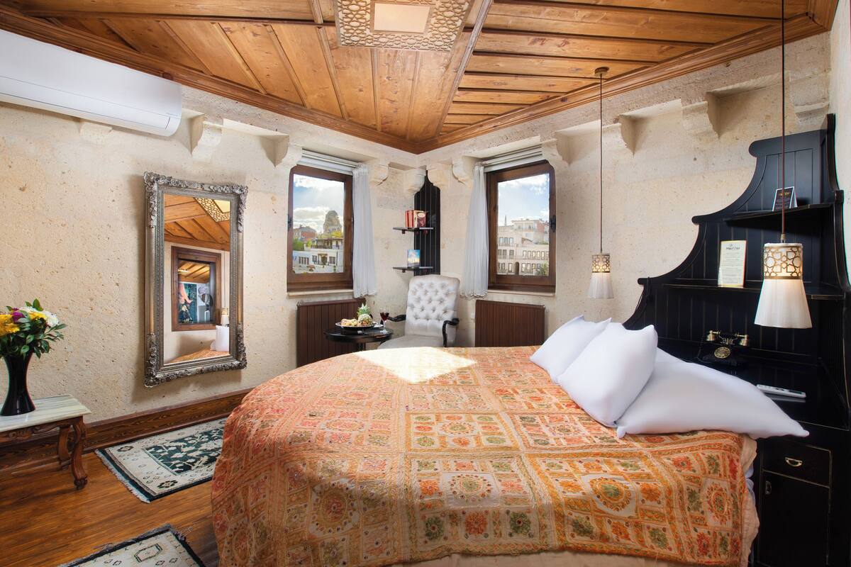 Un dormitorio con cama, espejo, ventana, piano y lámpara.