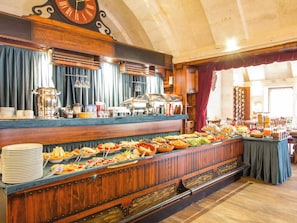 A buffet setup with various food items and a clock on the wall.
