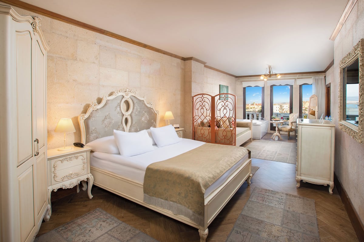 Un dormitorio amplio con una cama grande, un aparador, un tocador y un balcón con vistas.