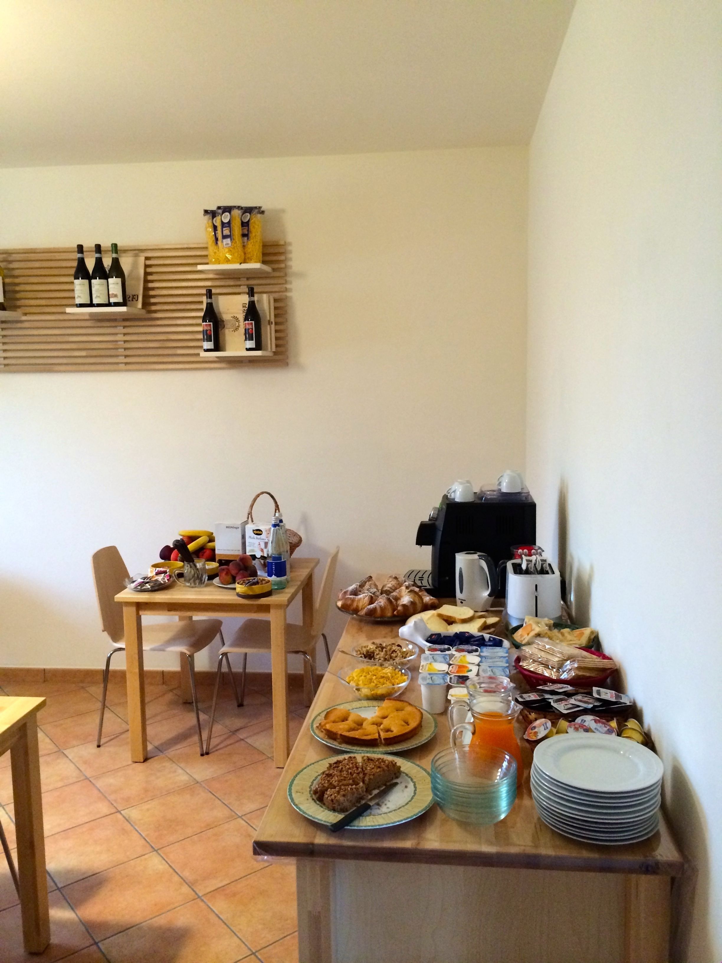 Ein Essbereich mit einem Holztisch, gedeckt für das Frühstück, inklusive Gebäck, Früchten und Getränken.