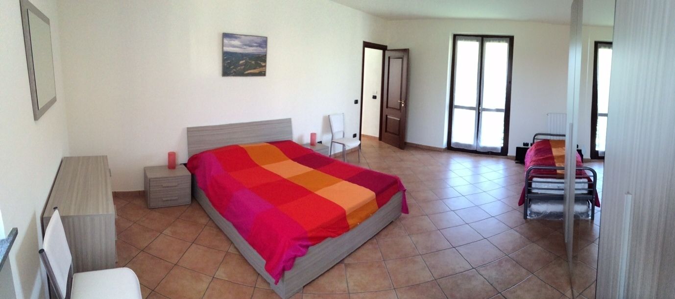 A bedroom with a bed, bedside tables, a chair, and a window.