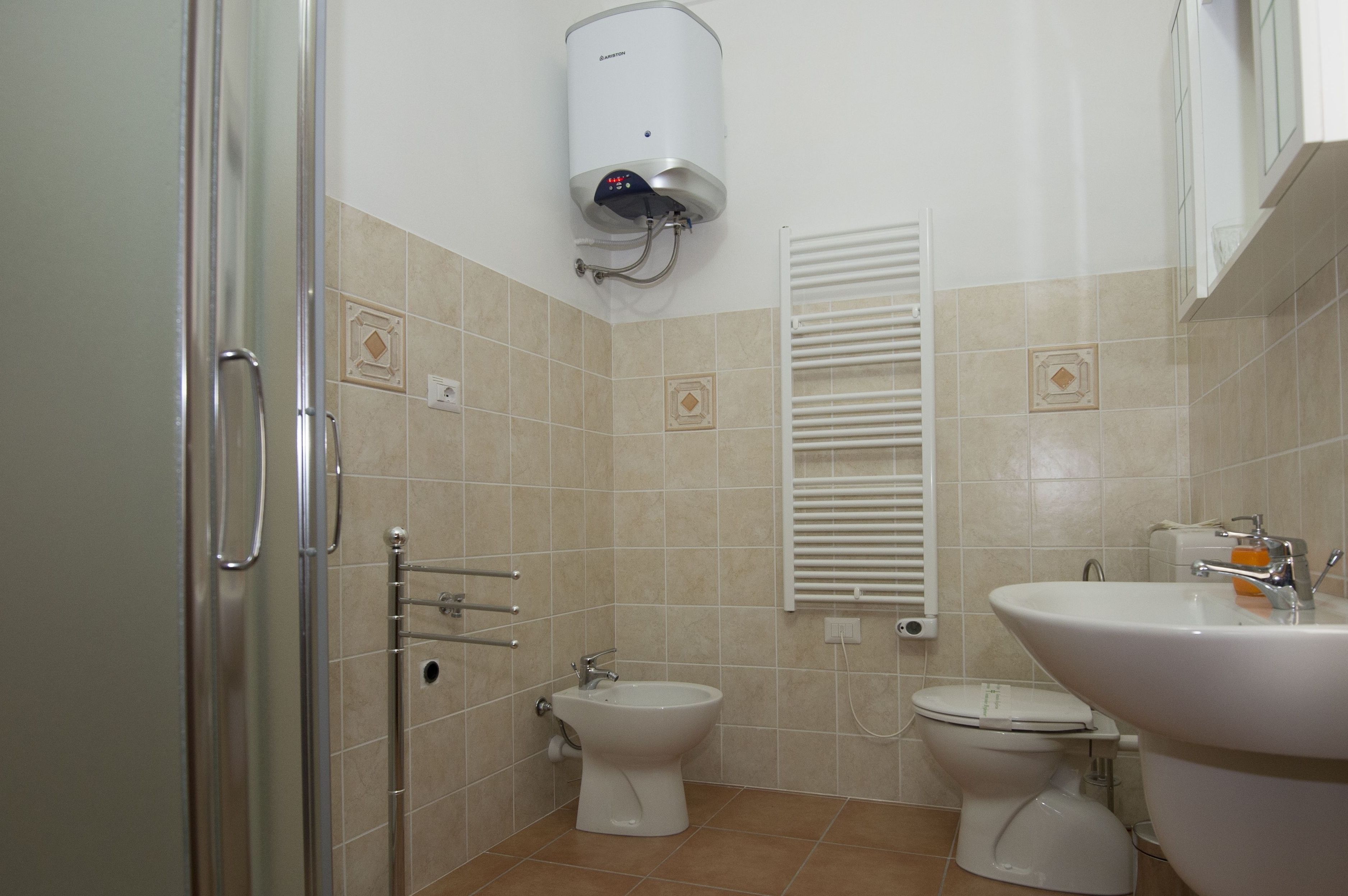 Ein Badezimmer mit Dusche, zwei Toiletten, einem Waschbecken und einem Handtuchhalter.