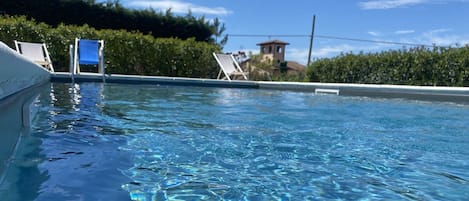 Una piscina al aire libre, sombrillas, sillones reclinables de piscina