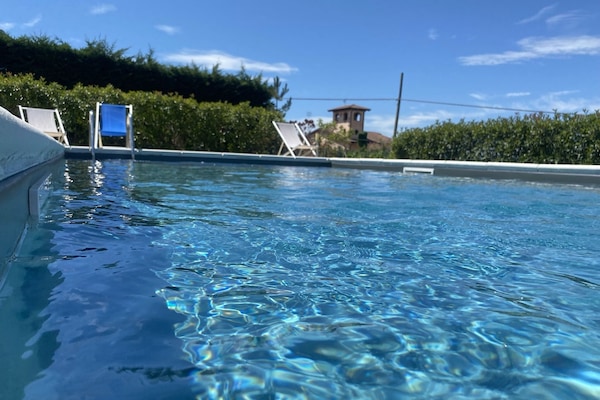 Una piscina al aire libre, sombrillas, sillones reclinables de piscina