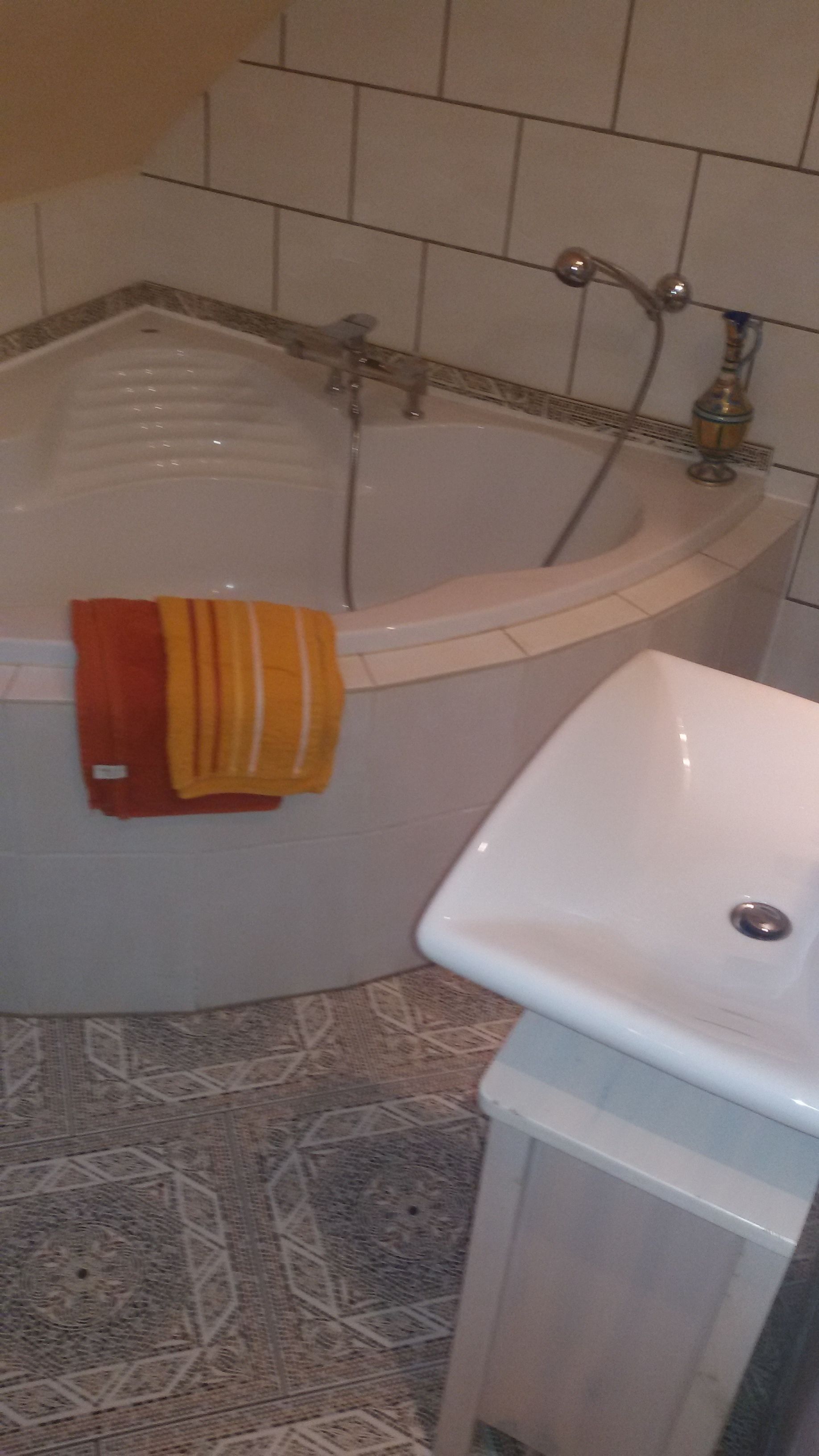 A bathroom with a bathtub, a white sink, and a patterned floor.