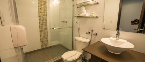 A modern bathroom with a glass-enclosed shower, a toilet, a sink with a mirror, and a towel rack.