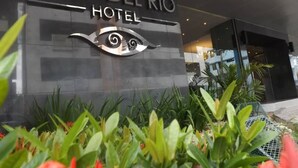The exterior of the Ojos del Rio Hotel with a modern design, featuring a prominent eye logo and lush greenery in front. - Hotel Ojos del Rio (Panama City)
