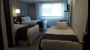 Habitación de hotel con dos camas, una mesita de noche con lámpara, una ventana con persianas y un aire acondicionado instalado en la pared.