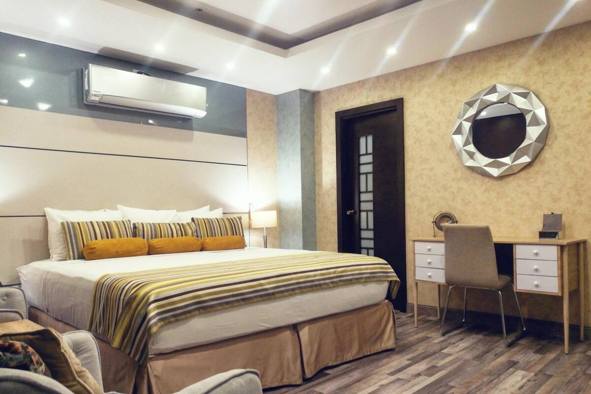 A modern hotel room with a large bed, a desk, and a chair.