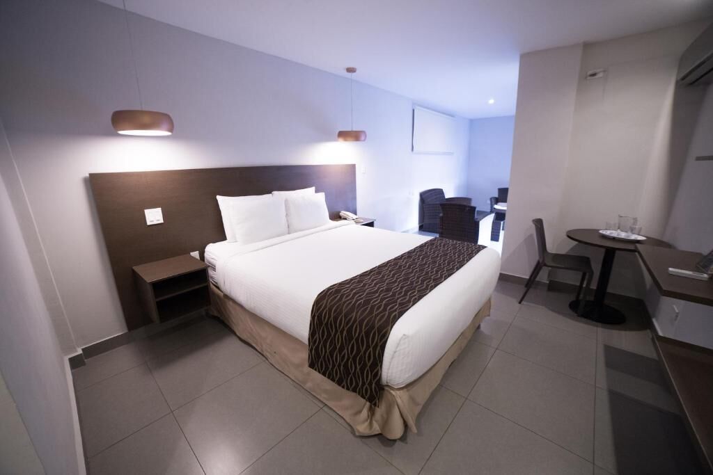 Une chambre d’hôtel avec un grand lit, des tables de chevet, un bureau et une chaise.