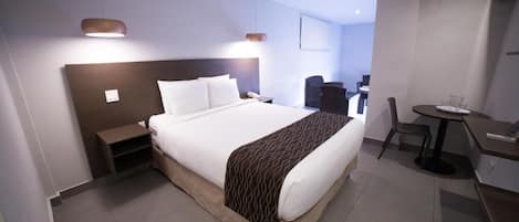 A hotel room with a large bed, bedside tables, a desk, and a chair.