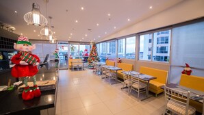 A modern hotel lobby with a Christmas tree, seating areas, and large windows offering city views. - Hotel Ojos del Rio (Panama City)