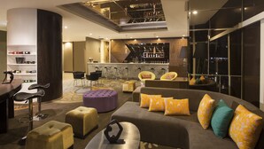 Un área de descanso moderna con bar, asientos y una escalera que sube a un nivel superior.