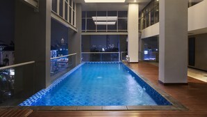 Una piscina interior con vistas a la ciudad, amplias ventanas y un diseño moderno.