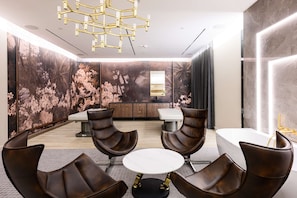 Une pièce moderne avec une table ronde, des fauteuils en cuir, un canapé blanc et un grand miroir.