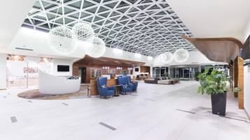 A spacious lobby with a high ceiling, modern seating, and a reception desk.