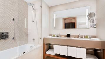 A modern bathroom with a glass-enclosed shower, a wooden vanity with a mirror, and a built-in shelf for towels.