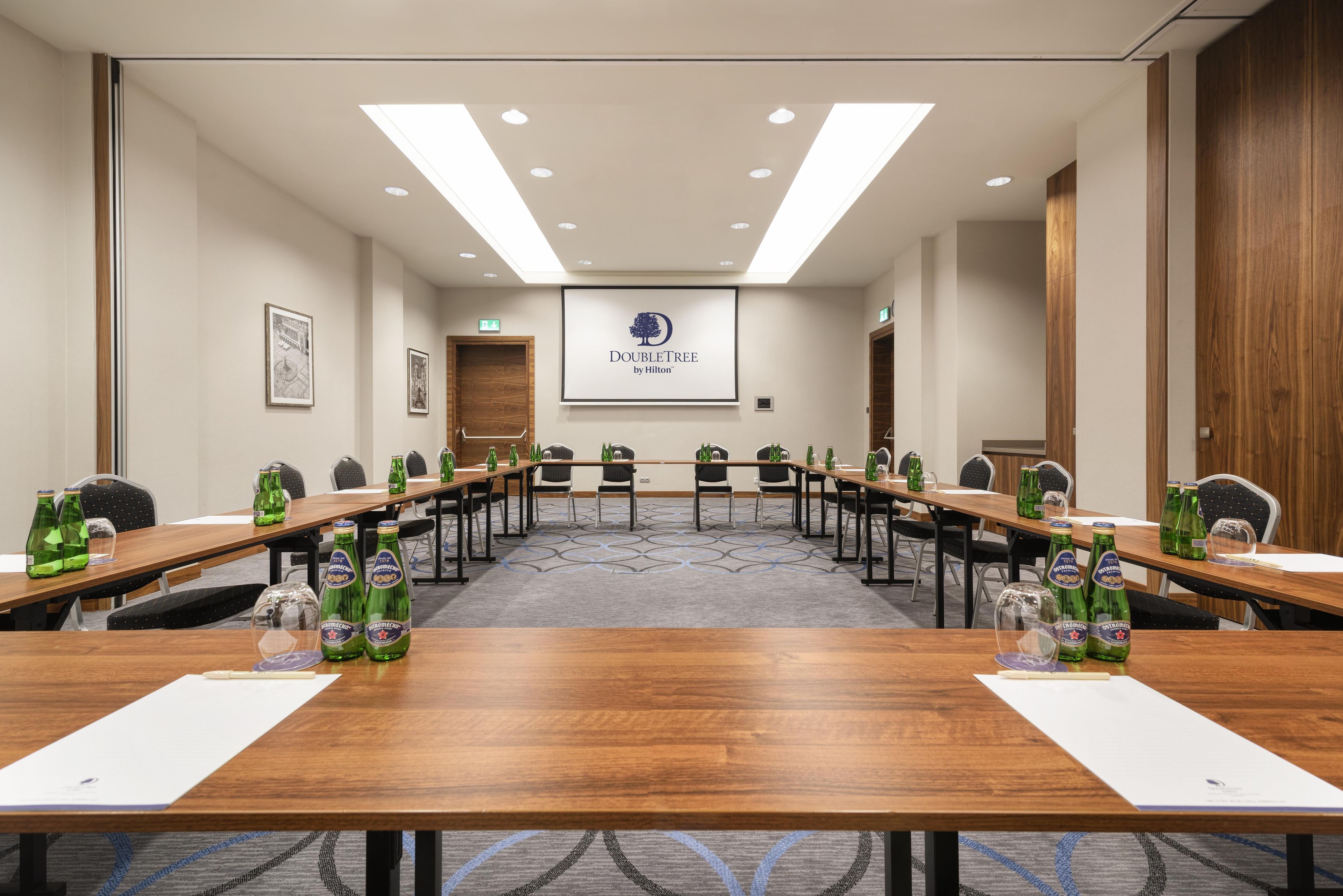 A conference room with a long table, chairs, and a screen displaying the DoubleTree by Hilton logo.