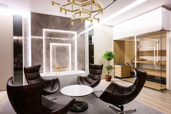 Une salle de réunion moderne dotée d’une table ronde, de fauteuils en cuir, d’une grande fenêtre et d’un sauna intégré.