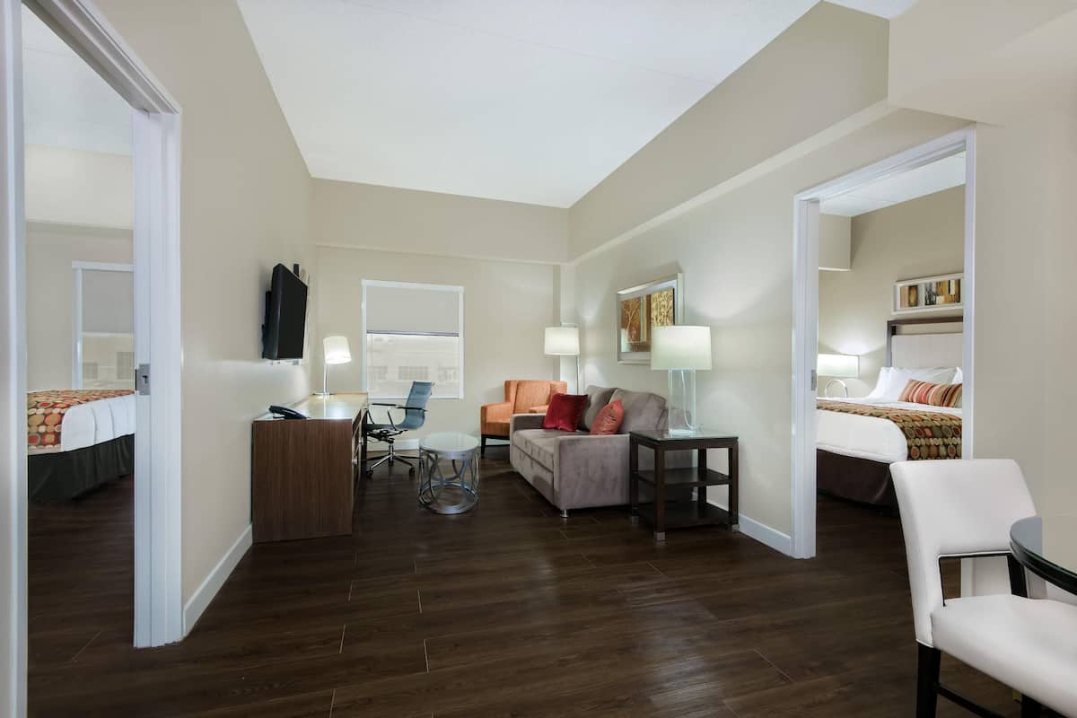 A hotel room with a bed, a desk, a chair, a sofa, and a small table.