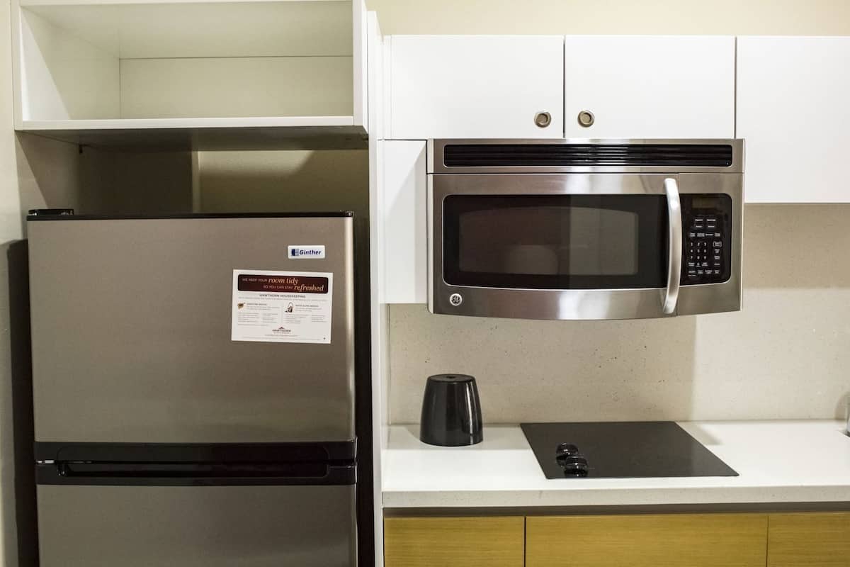 A kitchen with a stainless steel refrigerator, a microwave, and a coffee maker on the counter.