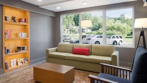 A living room with a beige sofa, a wooden coffee table, and a bookshelf filled with books. - Country Inn & Suites by Radisson, Gatlinburg, TN (Gatlinburg)