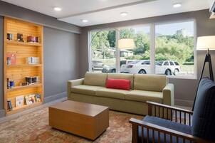 Una sala de estar con un sofá color beige, una mesa de centro de madera y una estantería llena de libros.
