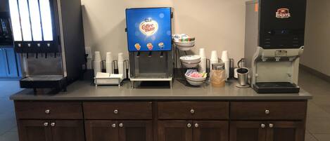 Una estación de café con varias máquinas de café y un dispensador de bebidas.