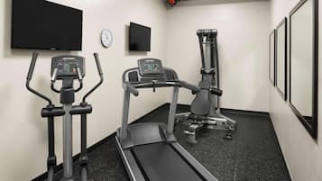 A fitness room with treadmills, a stationary bike, and a wall-mounted TV.