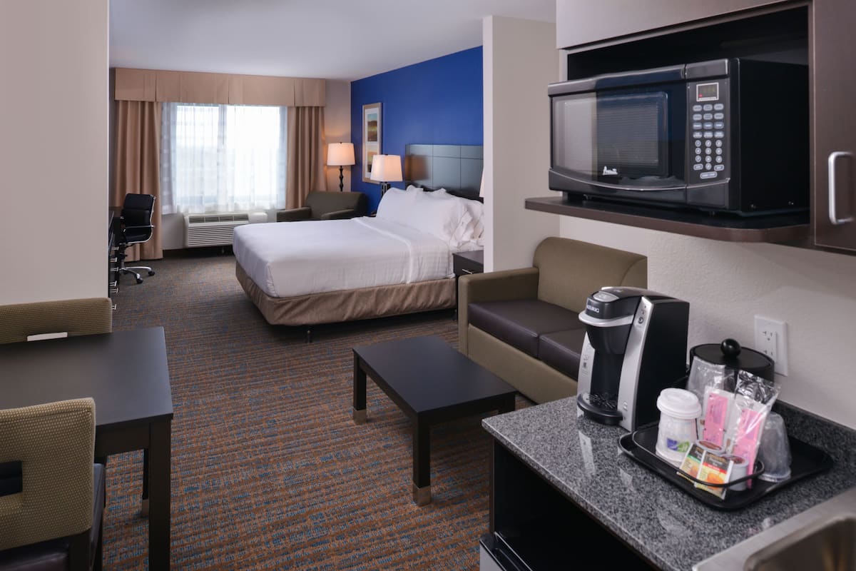 Ein Hotelzimmer mit einem Bett, einem Schreibtisch, einer Kaffeemaschine, einer Mikrowelle und einer Sitzecke.