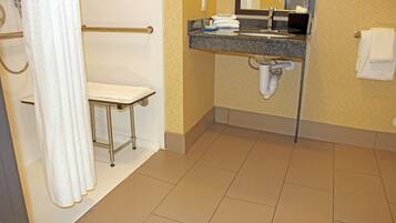 A hotel bathroom with a shower, toilet, sink, and towel rack.