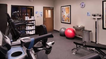 A gym with exercise equipment, a clock, and a framed abstract painting.