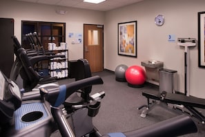 A gym with exercise equipment, a clock, and a framed abstract painting. - Holiday Inn Express & Suites Bakersfield Airport by IHG (Bakersfield)