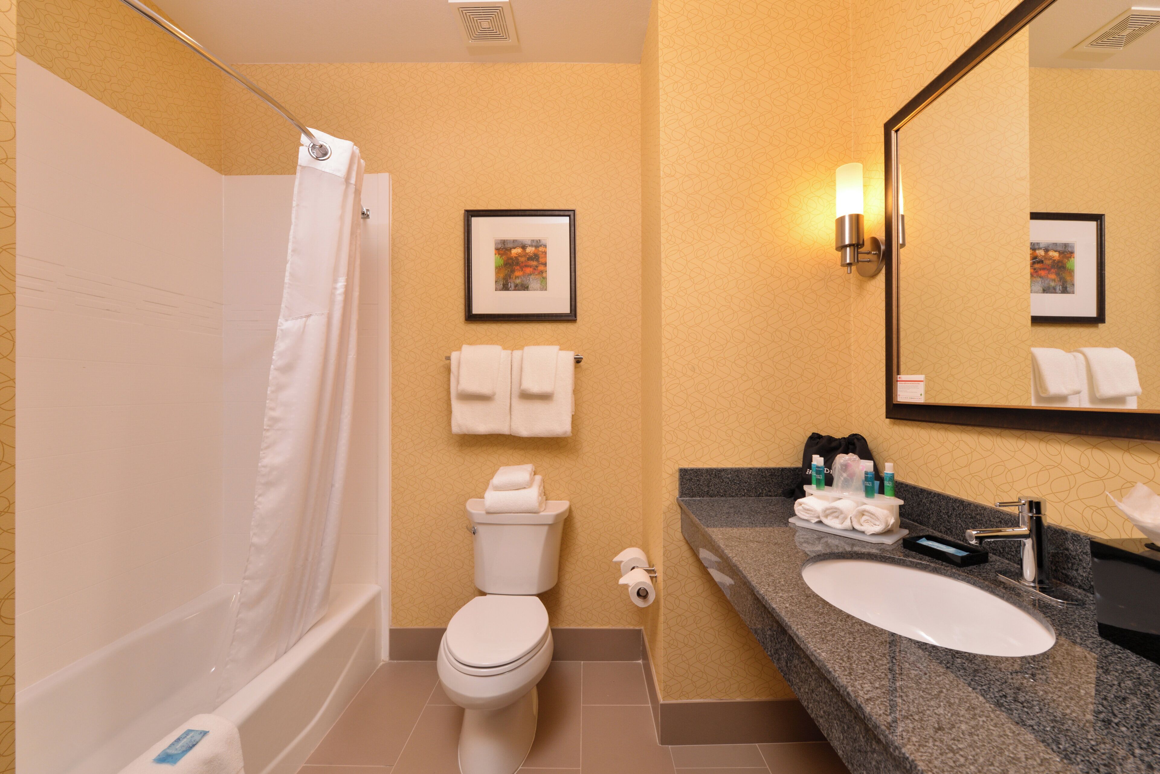 A bathroom with a bathtub, toilet, sink, and a framed picture on the wall.