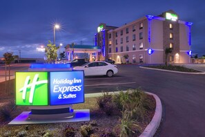 Letrero de Holiday Inn Express & Suites, con vista despejada a la entrada del hotel y coches aparcados.