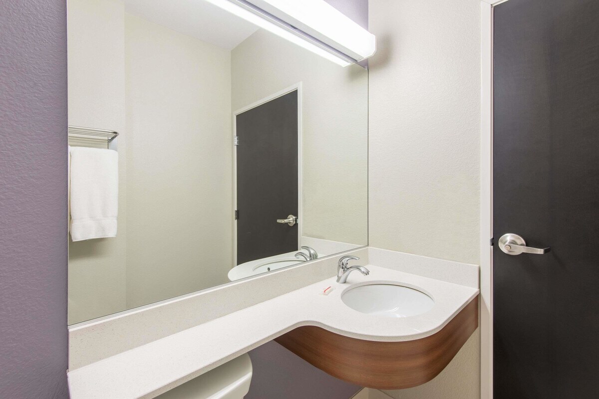 A bathroom with a white sink, a mirror, and a door.