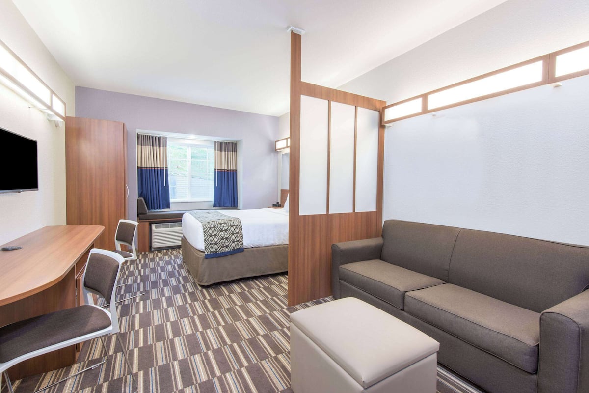 A hotel room with a bed, a sofa, a desk, and a TV.