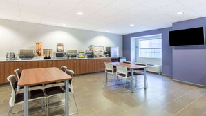 A modern kitchen area with a dining table and chairs, a microwave, and a coffee machine. - Microtel Inn & Suites By Wyndham Cadiz (Cadiz)
