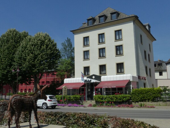 A hotel with a white facade, multiple windows, and a red awning. - Hotel Du Parc (Diekirch)