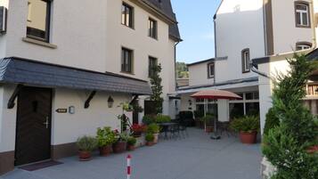 A courtyard with potted plants, outdoor seating, and a red umbrella.