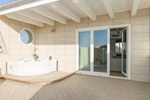A modern bathroom with a freestanding bathtub, a round mirror, and a potted plant. - Porto di Claudio (Fiumicino)