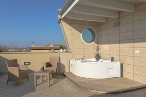 En tagterrasse med jacuzzi, fletstole og et bord.
