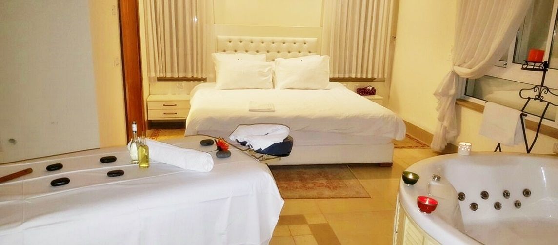 Una habitación de hotel con una cama, una camilla de masaje y una bañera.