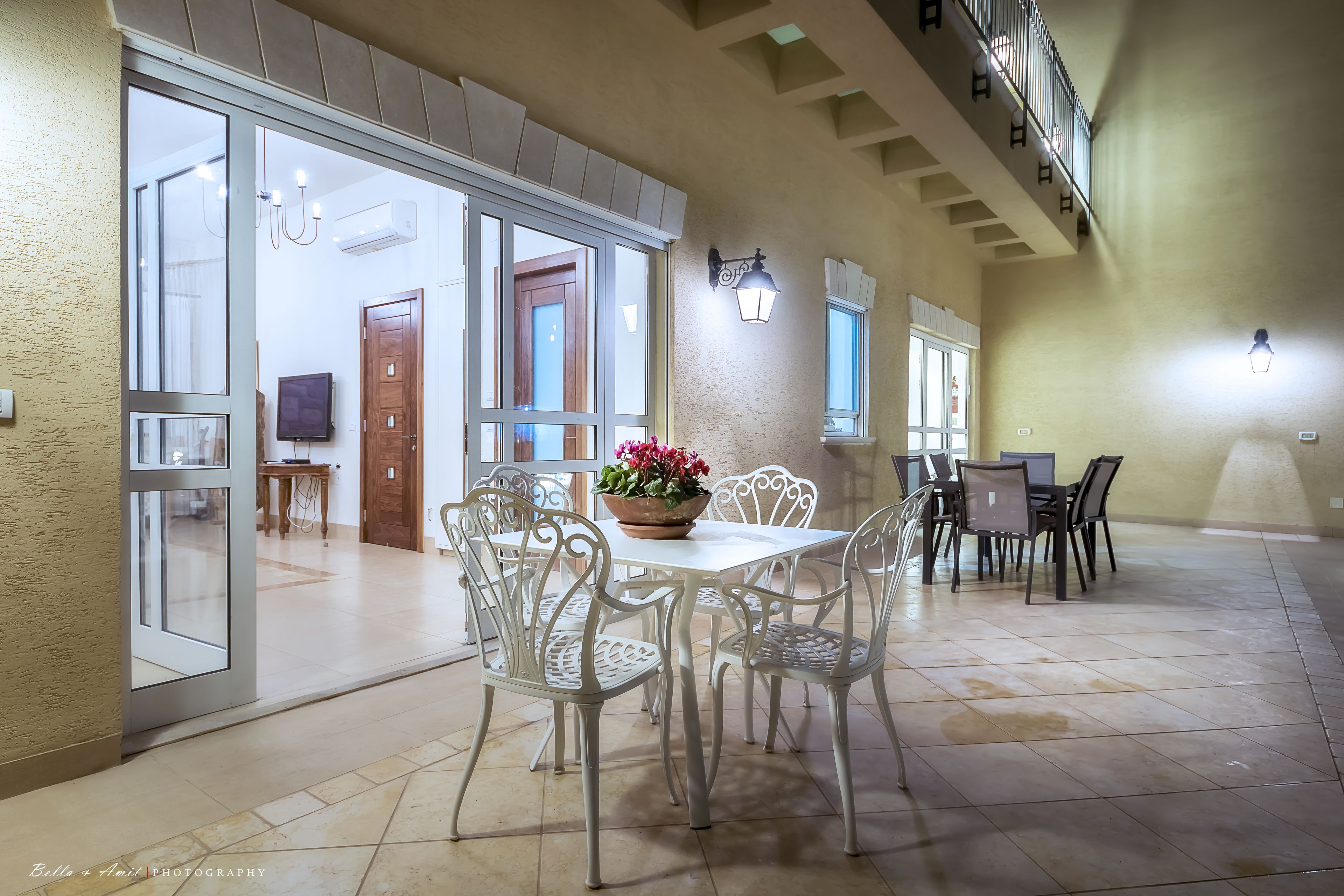 Un espacio interior amplio con una mesa de comedor y sillas, una planta en maceta y una escalera que sube a un nivel superior.