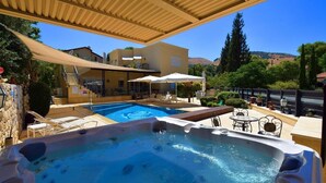 A pool area with a hot tub and lounge chairs, surrounded by a covered patio and a view of a hillside. - Villar (Rosh Pinna)