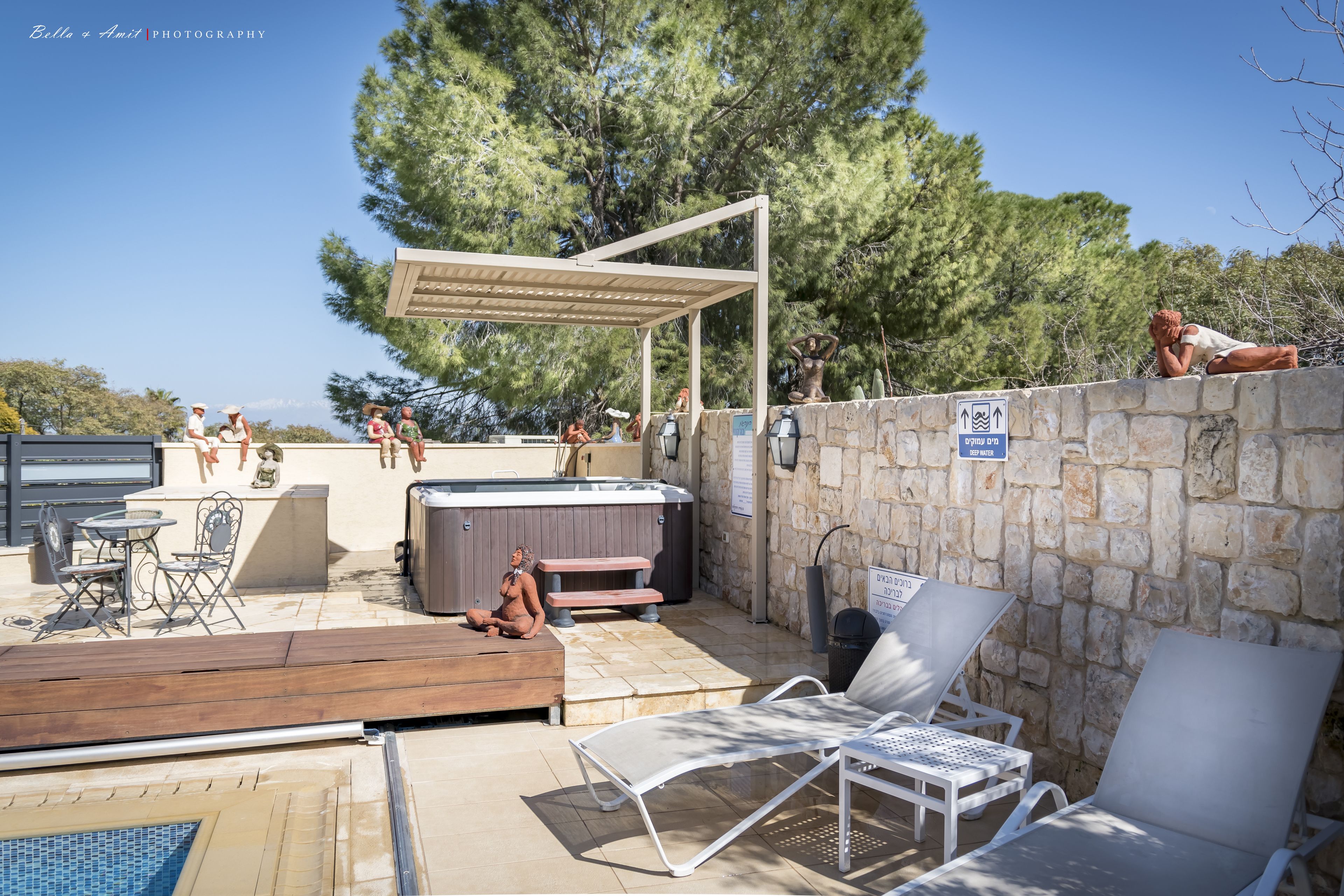 Un área de piscina al aire libre con sillones de descanso, un jacuzzi y un espacio de estar cubierto.