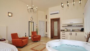 A spacious room with a large bathtub, two armchairs, a bed, and a kitchenette. - Villar (Rosh Pinna)