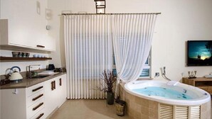 A bathroom with a bathtub, a shower curtain, a sink, and a mirror. - Villar (Rosh Pinna)